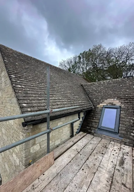 A rooflight set into a Cotswold stone slate roof, with the slates cut round it and flashed to the sides.